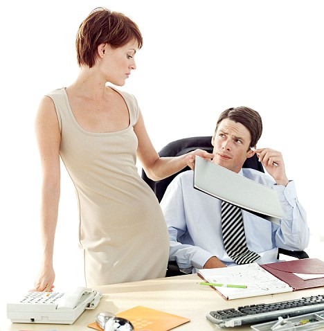 young woman handing a file to a male co worker sitting at his desk