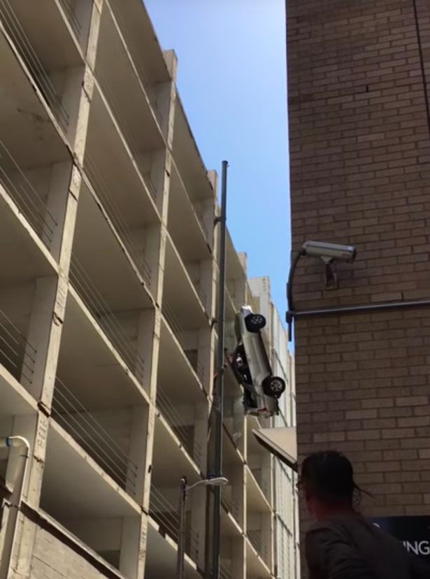 driver-crawls-out-of-car-dangling-off-side-of-parking-garage